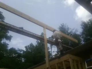 Carpenter setting a ridge beam over a new addition frame — Ice Dam Removal by Roofing Brothers in Ranson