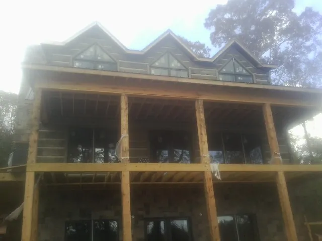 Dormers and porch framing on a large log home under construction — Roof Coating work by our crew in Ranson
