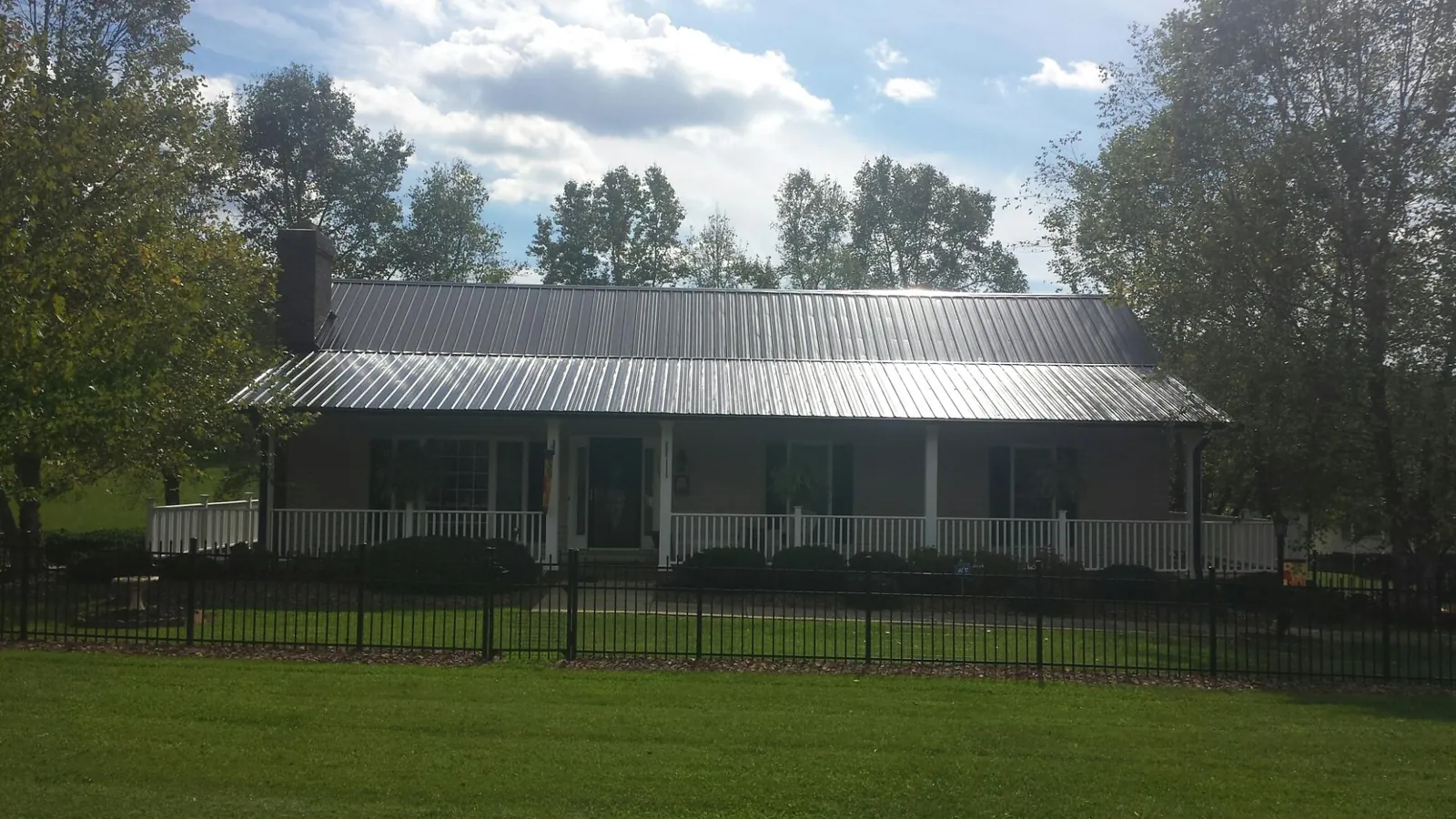 Gray metal roof on a brick ranch with a full width front porch — Gutter Guard Installation work by our crew in Ranson