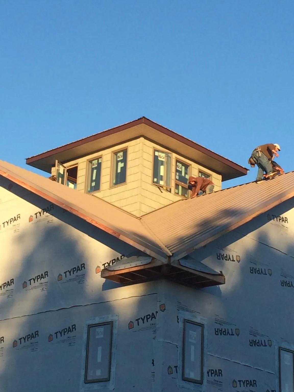 Roofers working around a rooftop cupola on a new metal roof at sunset — Roof Waterproofing in Ranson by Roofing Brothers
